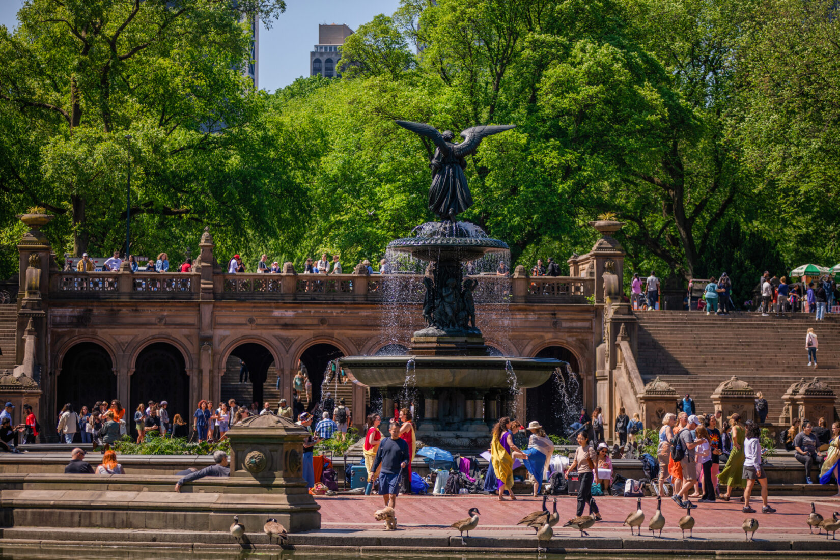 A large fountain with crowds of people walking around it.