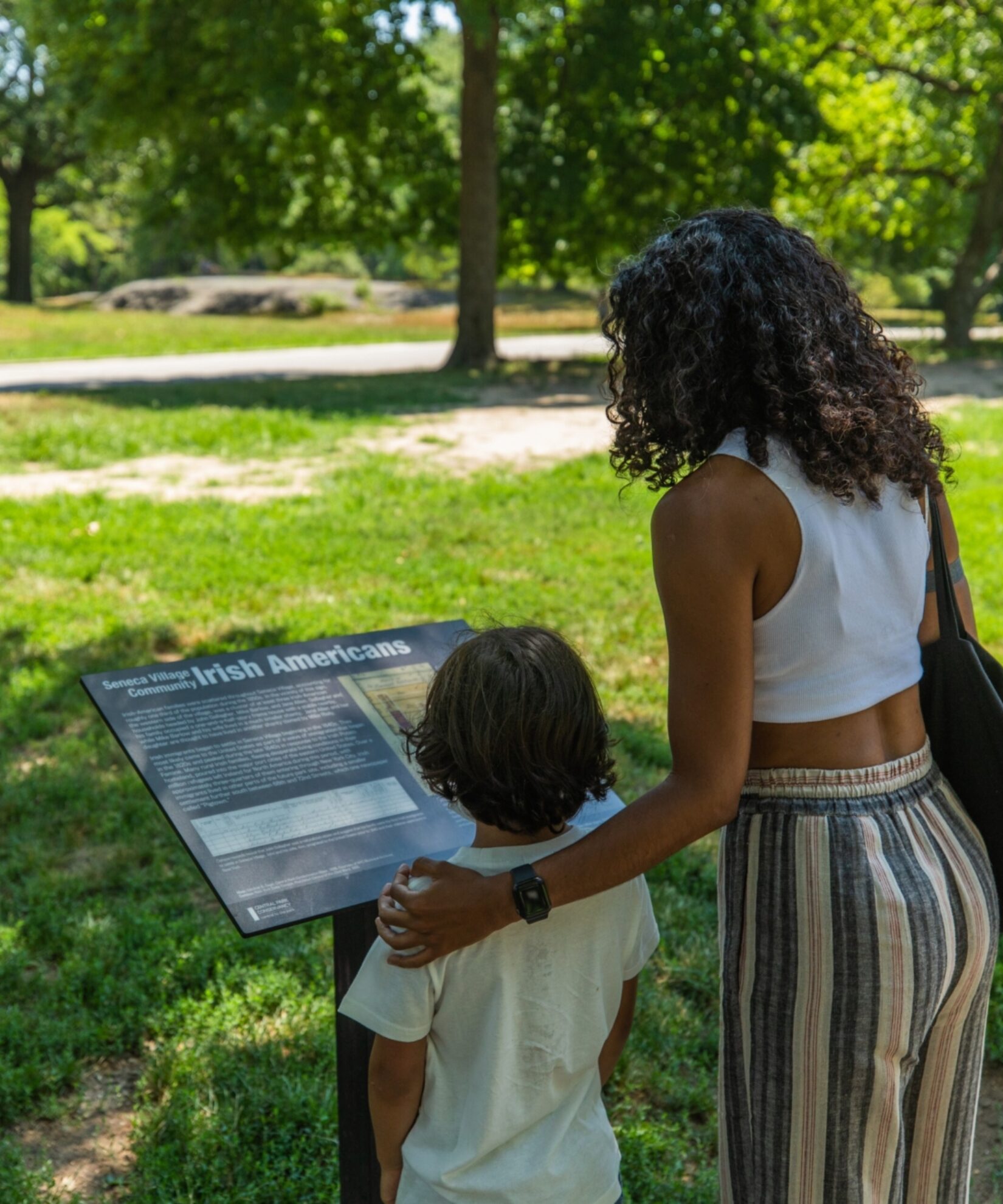Two park goers reading one of the in-park signs celebrating the history of Seneca Village